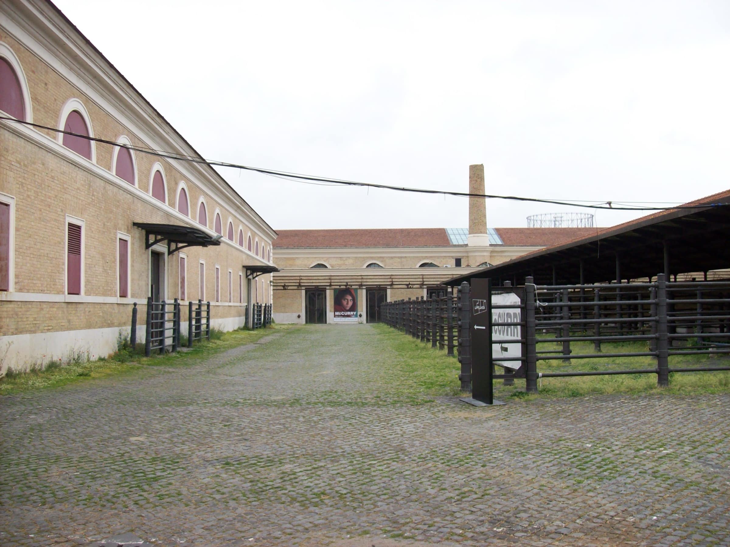 Cour de l'ancien abattoir de Testaccio, enclos à bétail en fonte conservés, affiche d'exposition au fond