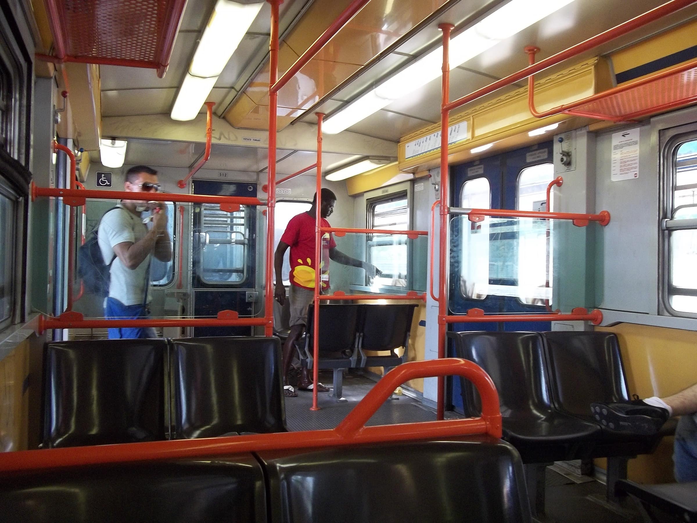 Intérieur d'un train de la ligne Roma-Lido, wagon un peu daté, barres oranges, quelques passagers