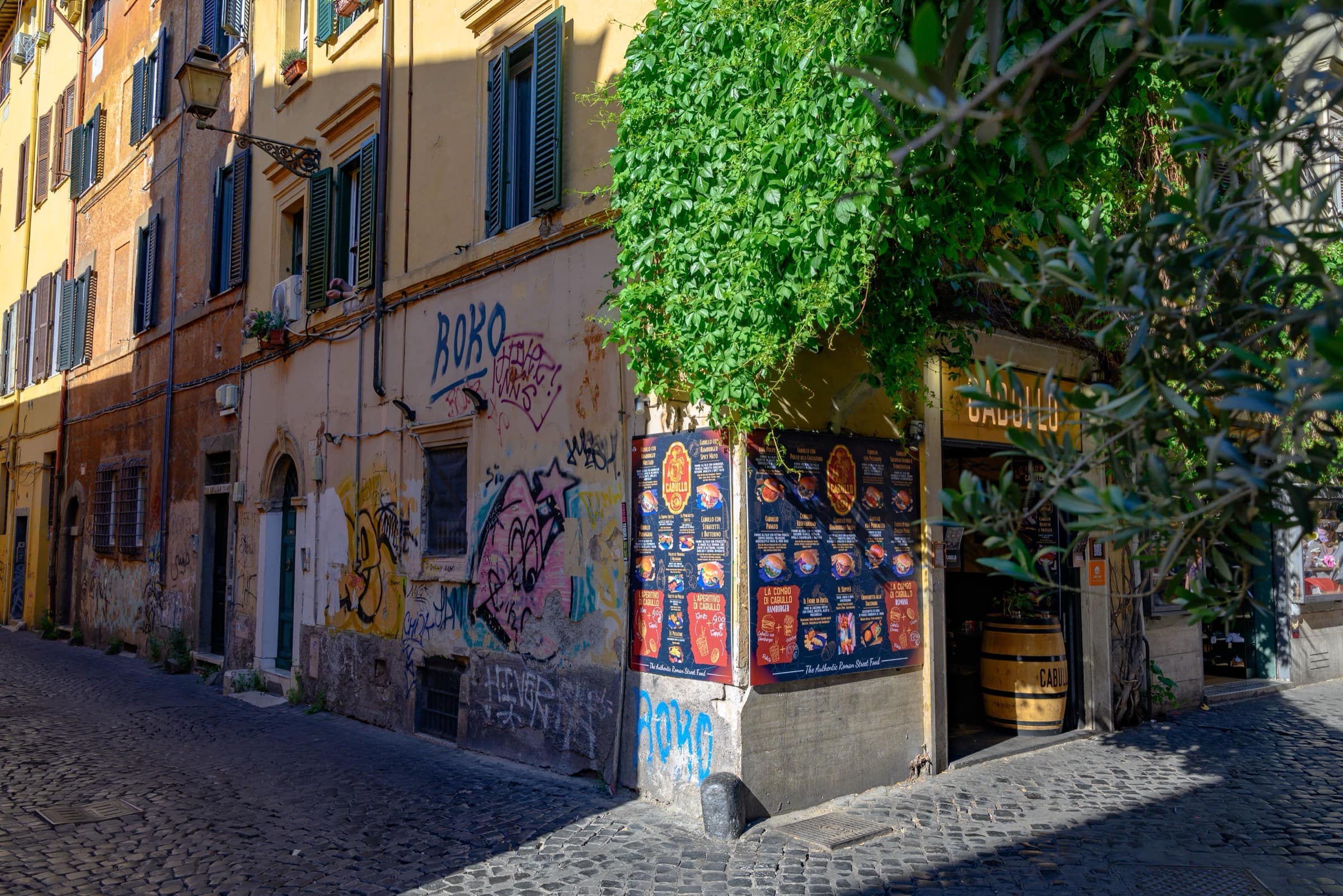 Une ruelle pavée de Trastevere au petit matin, façade ocre, lierre et rideaux baissés