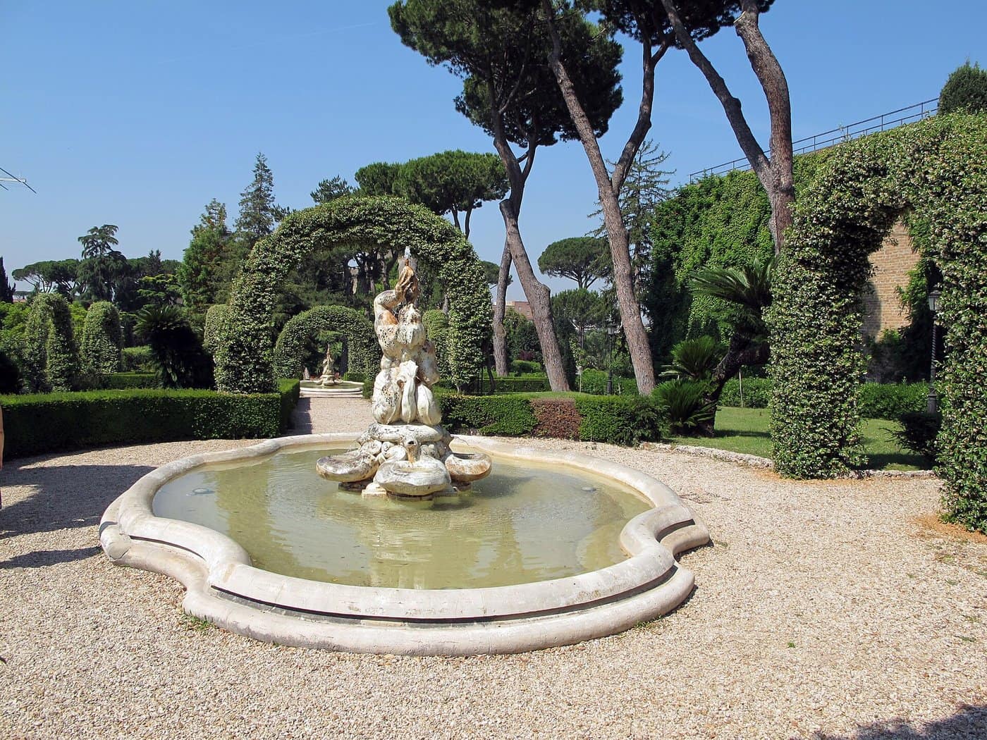 Les jardins du Vatican : la coupole de Saint-Pierre au-dessus des arbres, les parterres à la française et les fontaines baroques.